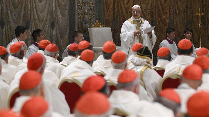 El Papa Francisco lee un documento desde un atril con micrófono ante una audiencia de cardenales vestidos con sus ropas tradicionales en una sala del Vaticano.