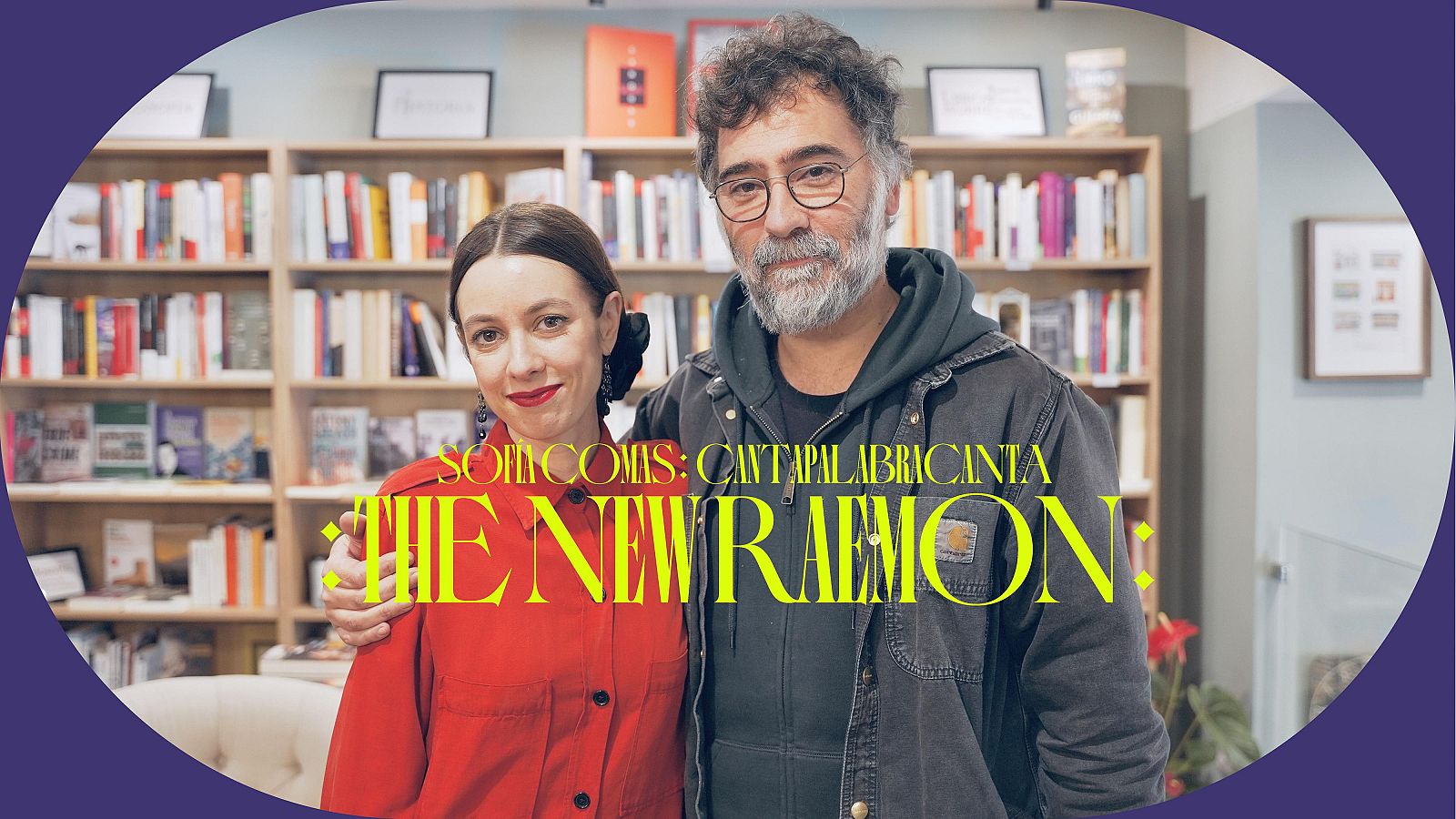 Dos cantantes posan juntos en una librería; él con chaqueta oscura y gafas, ella con camisa roja. La imagen tiene un marco ovalado morado y texto superpuesto.