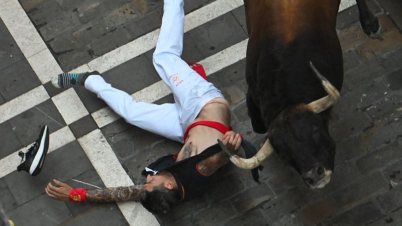 Un toro arrastra a un corredor por la camiseta durante varios metros en el tercer encierro de San Fermín 2025