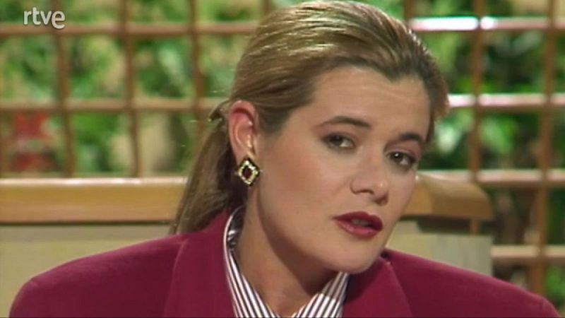 Elena Ochoa, psicóloga y sexóloga, en un plató de RTVE con chaqueta fucsia y camisa de rayas. Primer plano con maquillaje y pendiente.