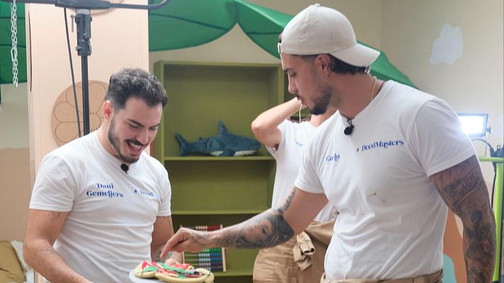 Dos hombres posan en un set, uno señalando galletas decoradas y el otro sonriendo. Ambos llevan camisetas con el logo \"Decomasters\".