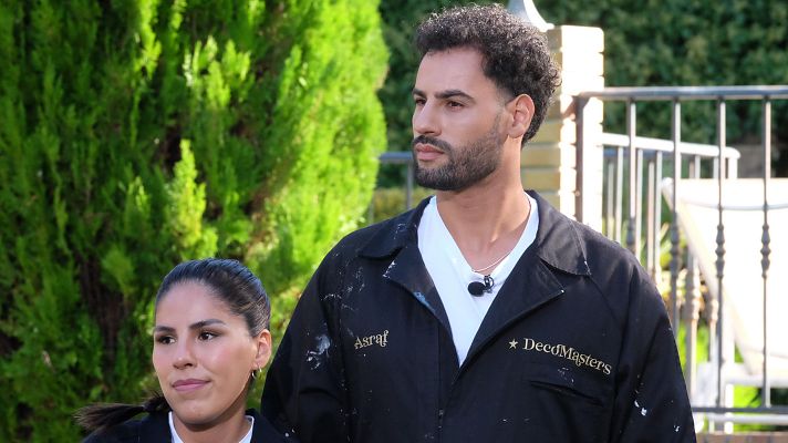 Isa Pantoja y Asraf Beno posan juntos, ambos vestidos con ropa de trabajo oscura y con manchas de pintura. Asraf lleva una camiseta blanca y un micrófono, con su nombre y \"DecoMasters\" visibles en su ropa.