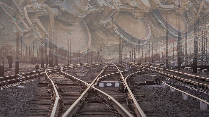Una compleja red de vías de tren metálicas, dispuestas sobre balasto de grava, se cruzan y entrelazan, con la superposición de ruedas de trenes en la parte superior y postes verticales en el entorno.