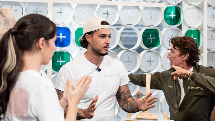 En un estudio con un fondo colorido, un hombre con gorra y camiseta blanca gesticula, mientras que una mujer aplaude y otro hombre con un mono de trabajo verde oliva señala.