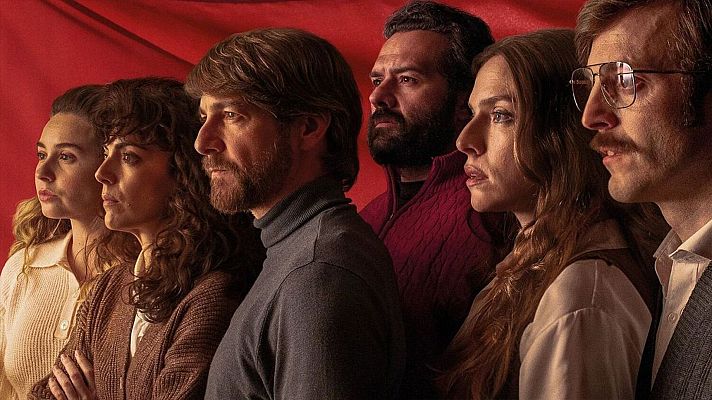 Un grupo diverso de seis personas, con diferentes estilos y edades, posan juntos mirando hacia la izquierda, con un fondo rojo intenso. Destacan las camisas blancas y los jerséis de cuello alto.