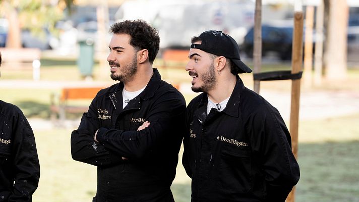 Dos jóvenes con barba y bigote, vestidos con monos de trabajo negros, posan para la cámara. Uno de ellos lleva una gorra. En sus pechos se leen las palabras \"Jesús\" y \"DecoMasters\".