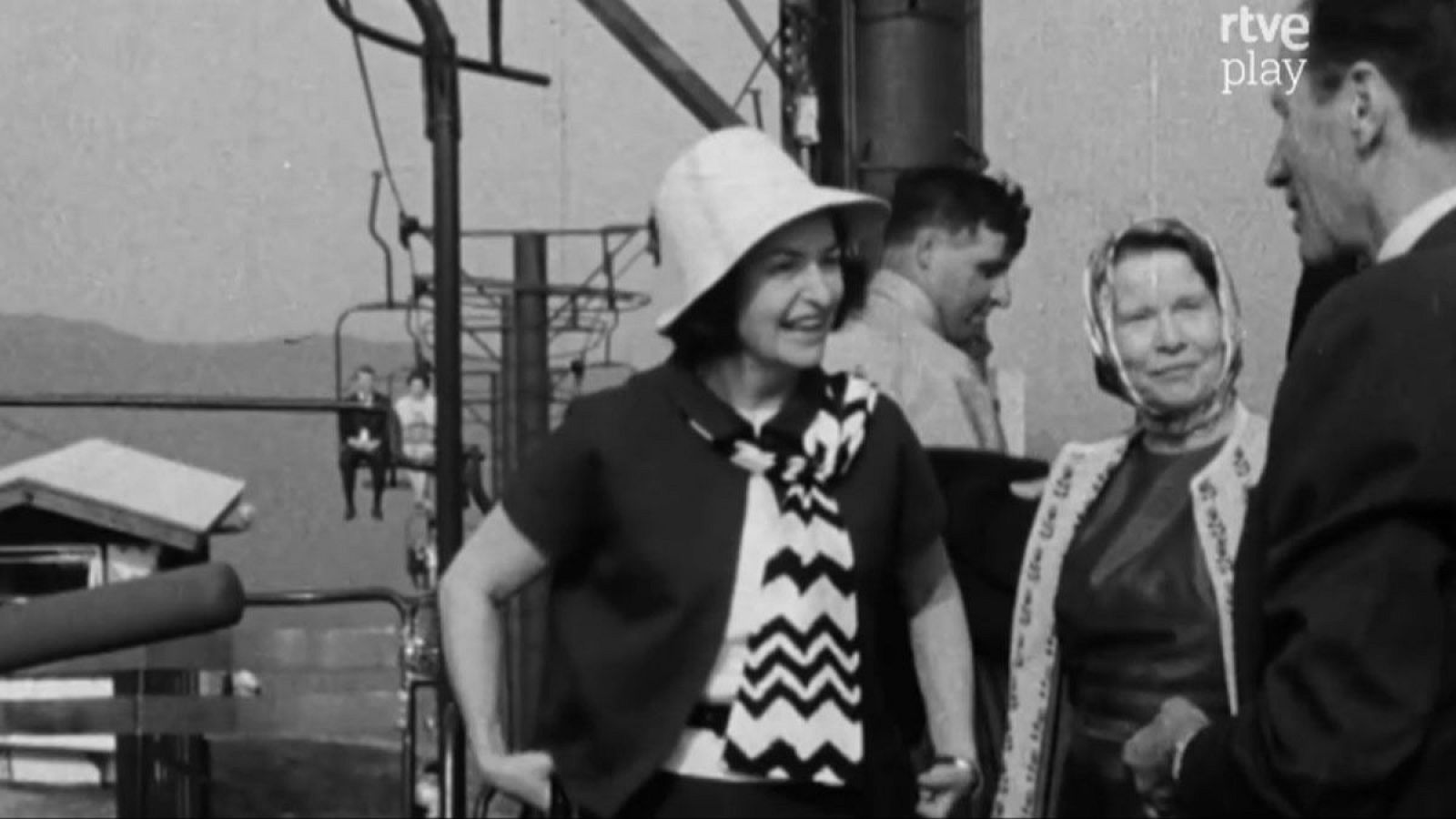 Lady Bird Johnson, sonriente con sombrero y bufanda de zigzag, posa junto a otra mujer con un telesilla y montañas de fondo. Logo de RTVE Play en la esquina superior derecha.