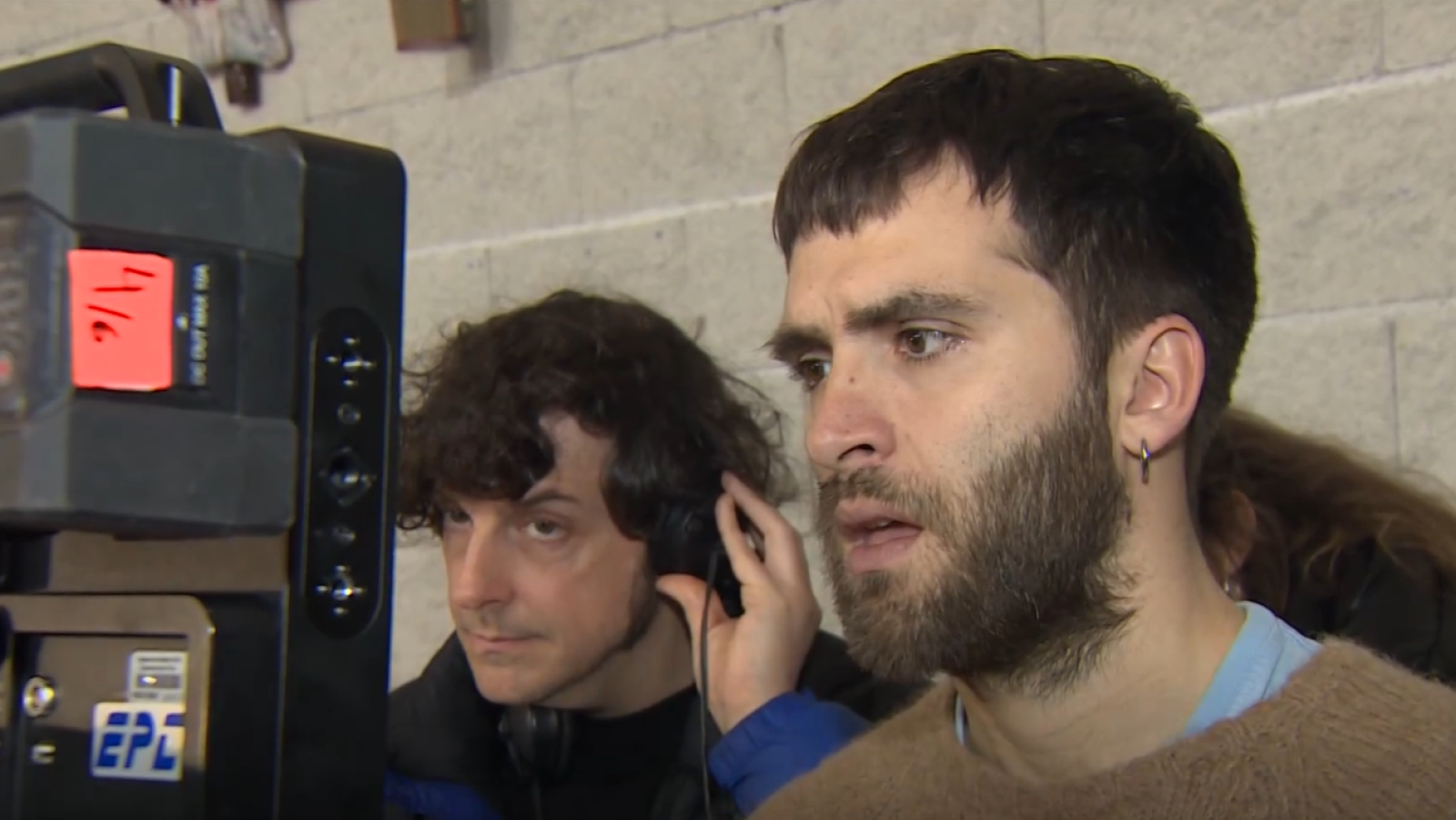 Ricardo Gómez, con barba y pendiente, dirige su primera película. Se observa un equipo de grabación con la inscripción "EPL" y la fecha "11/6", mientras otra persona con auriculares está presente en el rodaje.