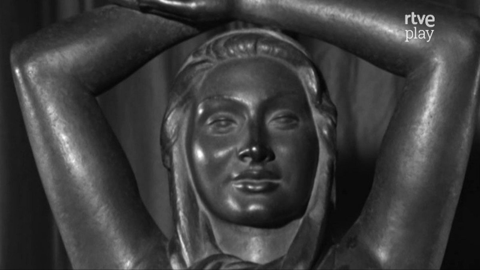 Escultura femenina en metal con brazos levantados y velo, imagen en blanco y negro. Se aprecia el logo de "rtve play" en la esquina superior derecha.