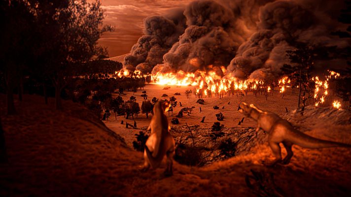 Un paisaje prehistórico devastado por un incendio muestra dos dinosaurios en primer plano, uno de pie y un Tyrannosaurus Rex, con un incendio forestal al fondo generando humo y llamas.