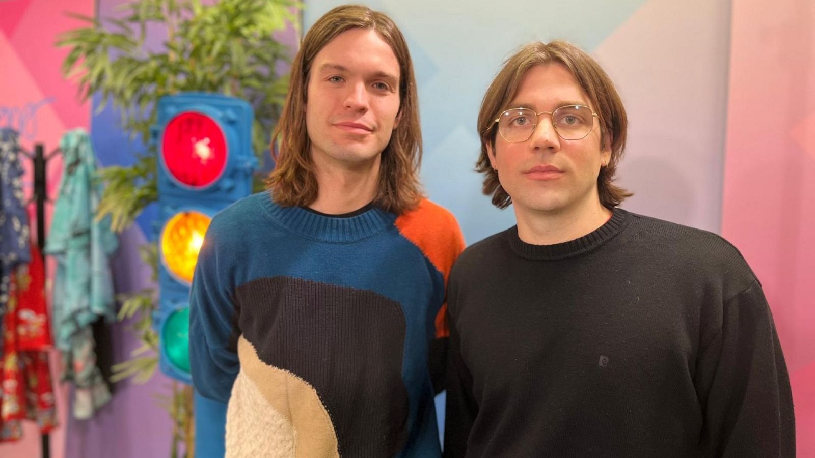 Carlos Vera y Marcos Crespo de Cora Yako posan en un estudio vibrante. Carlos lleva un jersey multicolor y Marcos gafas y jersey negro.