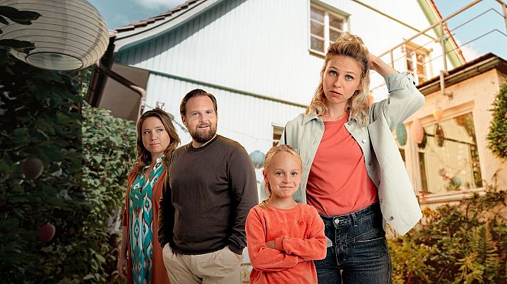 Familia posando en un jardín soleado frente a una casa, con detalles de vegetación y linternas decorativas. La niña sonríe con los brazos cruzados, mientras los adultos muestran expresiones variadas.