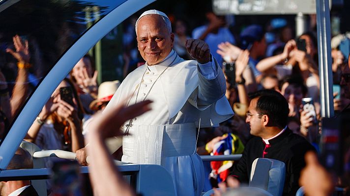 Papa Benedicto XVI saluda desde un Papamóvil descapotable a una multitud que lo graba con sus móviles. Viste sotana blanca y solideo.