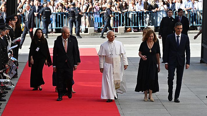 León XIV, Pedro Sánchez, Francina Armengol y Pedro Rollán, figuras prominentes, transitan por una alfombra roja en un evento oficial al aire libre.
