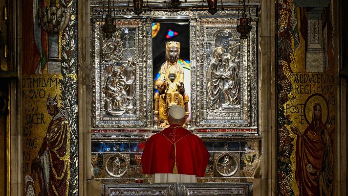 Papa León XIV de espaldas, frente a la estatua de la Virgen de Montserrat \"La Moreneta\" en la Abadía de Montserrat. Detalle del retablo y mosaicos.