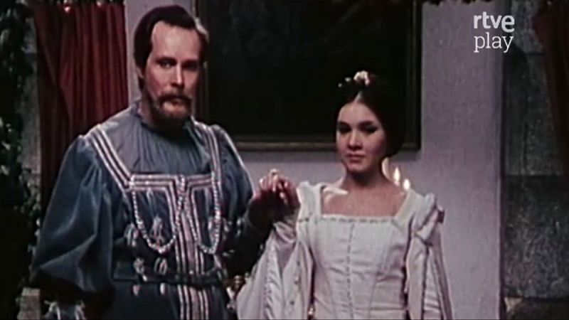 Jos� Mar�a Rodero y Victoria Vera, actores de �poca, se toman de la mano en una escena con vestuario detallado y un fondo oscuro con elementos rojos y verdes. Logo de rtve play en la esquina superior derecha.