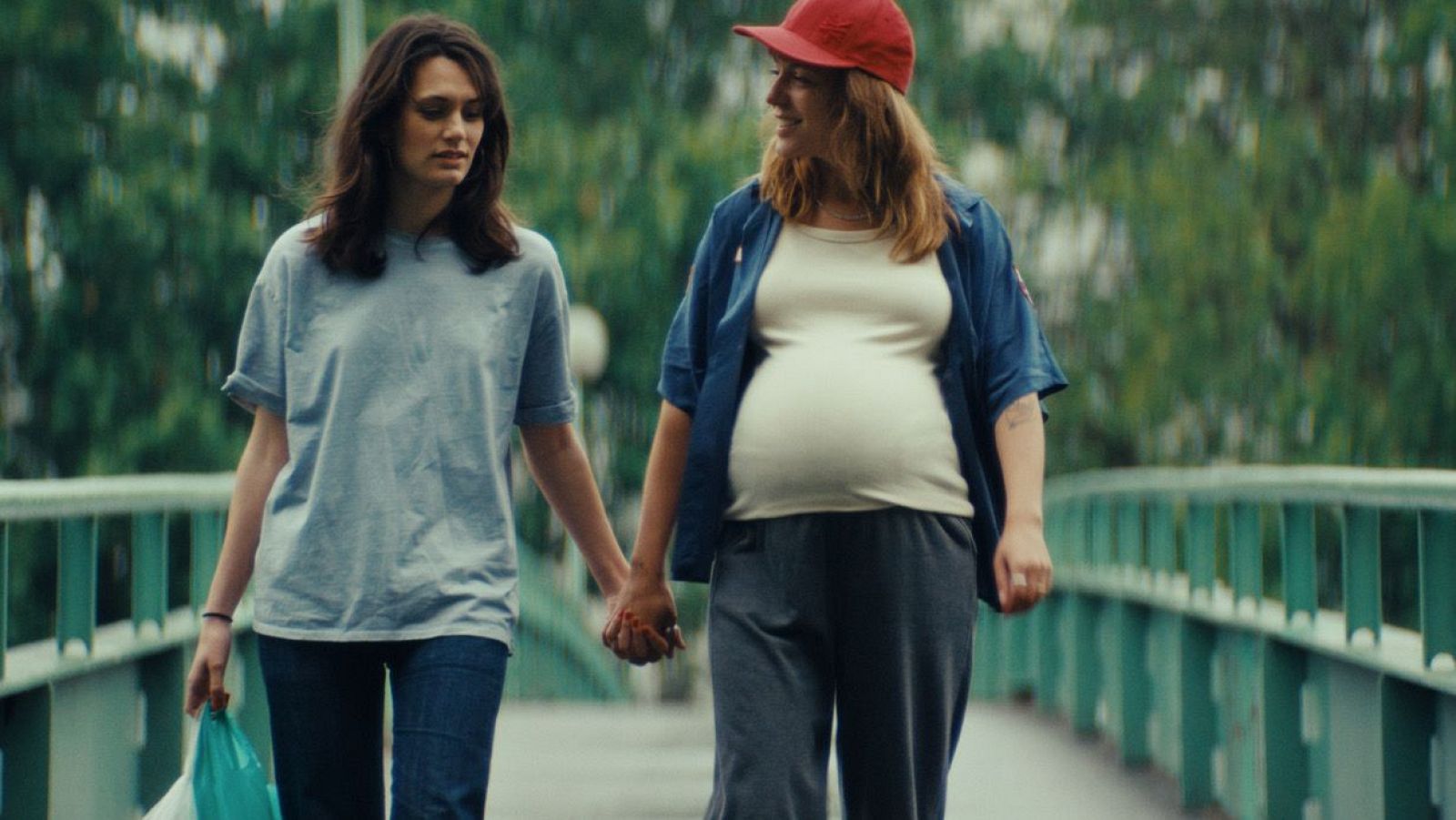 Dos mujeres, una embarazada, caminan de la mano sobre un puente. Fotograma de "15 pruebas de amor" en "Días de cine".