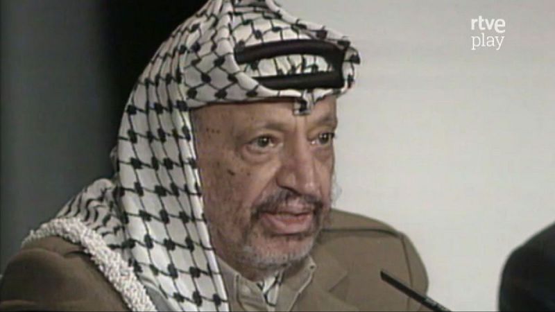 Primer plano de Yassir Arafat con su keffiyeh, micr�fono y el logo "rtve play".