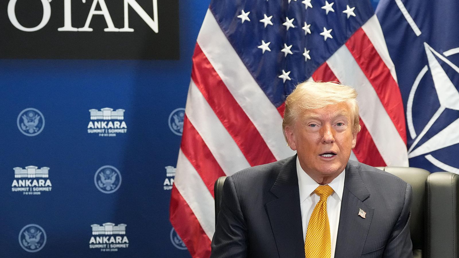Primer plano de Donald Trump con traje oscuro y corbata amarilla, frente a un fondo con las banderas de EE.UU. y la OTAN, y texto de la "ANKARA SUMMIT".