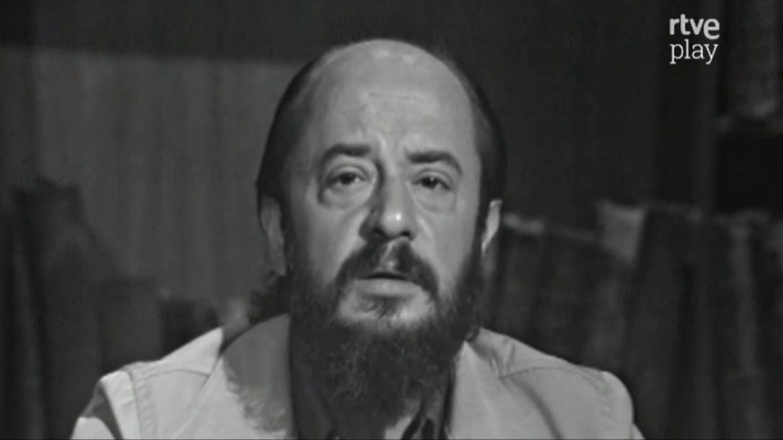 Plano medio corto de Fernando Jiménez del Oso, con calvicie, barba y bigote, mirando al frente. Logo de "rtve play" en la esquina superior derecha. Fondo oscuro y desenfocado.