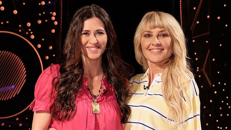 Marilia Andrés Casares y Cayetana Guillén Cuervo posan sonrientes en un estudio de televisión con luces de bokeh y un diseño circular abstracto.