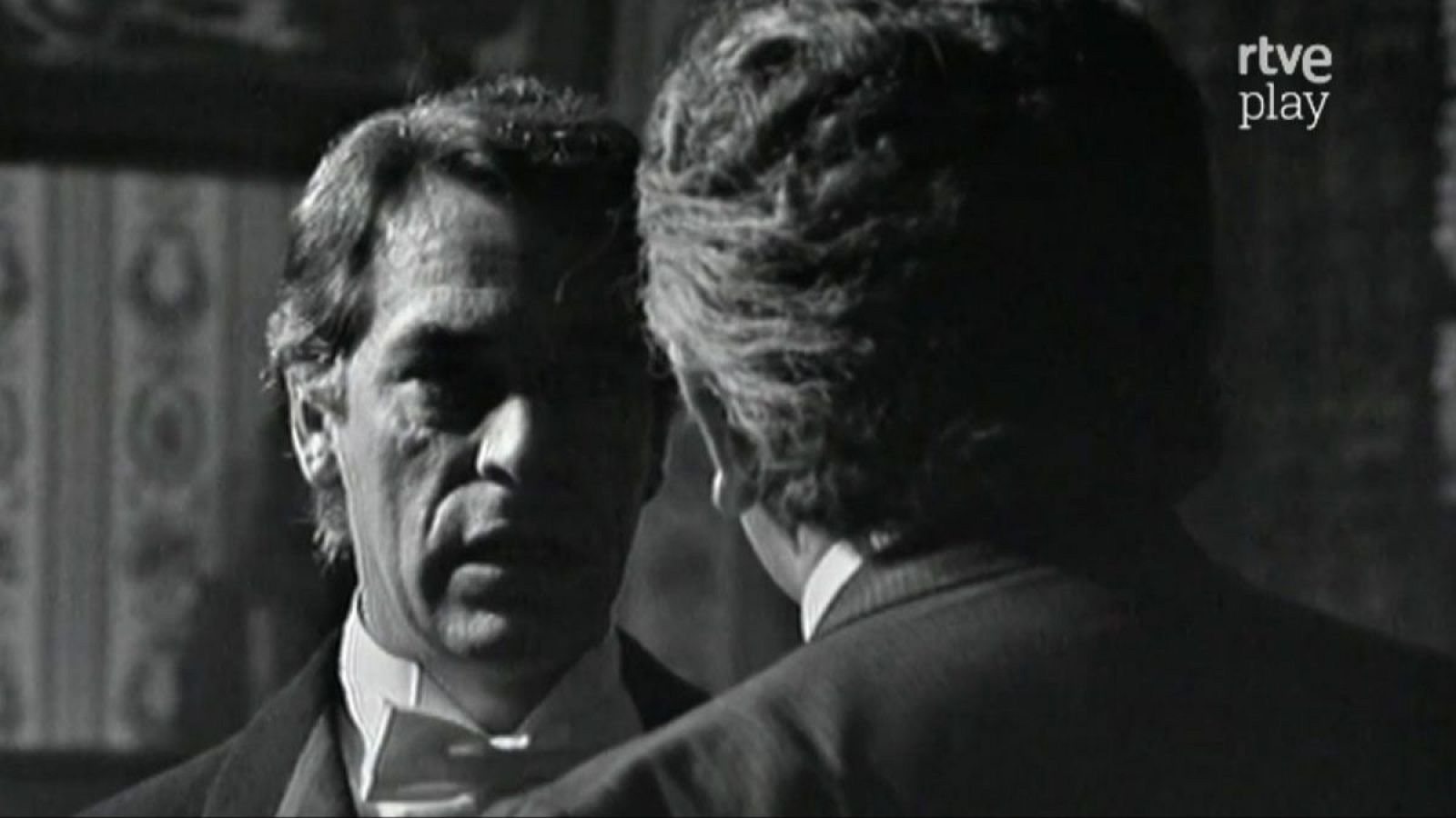 Primer plano de José Bódalo en blanco y negro, con expresión seria, junto a otro hombre de espaldas. Logo "rtve play" en la esquina superior derecha.