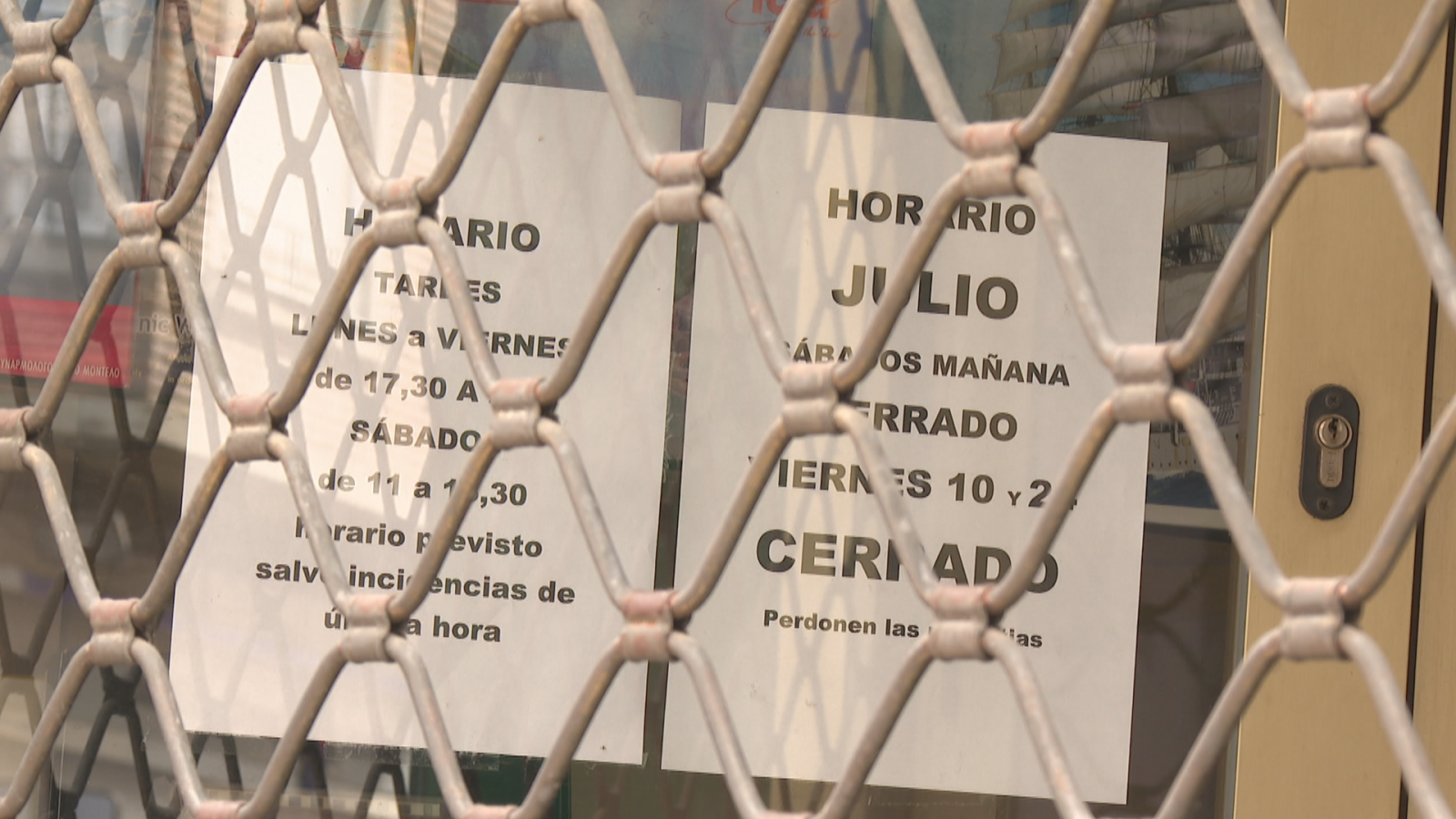 Entrada de un negocio cerrado con persiana metálica. Carteles informan horario habitual y cierre temporal en julio: Sábados mañana y viernes 10 y 2 cerrados. Perdonen las molestias.