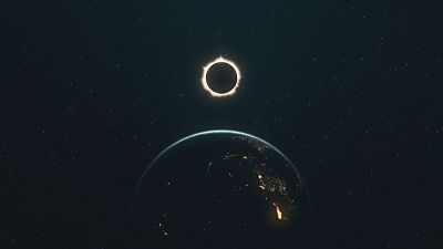 Eclipse solar total desde el espacio, con la corona solar visible y la Tierra iluminada por luces urbanas bajo una atm�sfera azul.