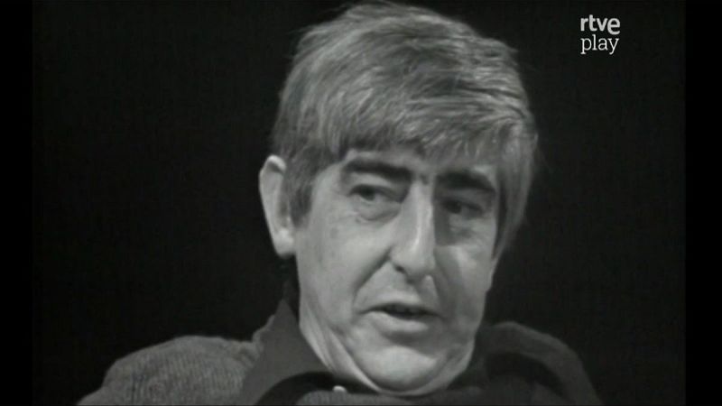 Primer plano en blanco y negro del escritor Juan Benet, con pelo canoso y expresión concentrada. Logo de "rtve play" en la esquina superior derecha.