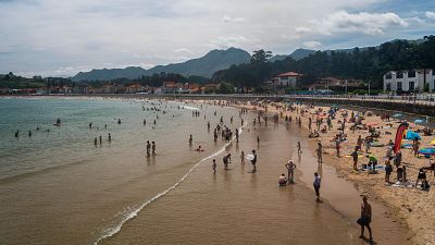 Numerosas personas disfrutan en la playa de Santa Marina, en Ribadesella, durante el verano.
