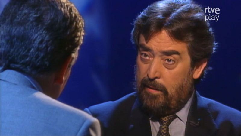 Primer plano de Javier Krahe en estudio de TV, con barba y traje. Se ve logo "rtve play".