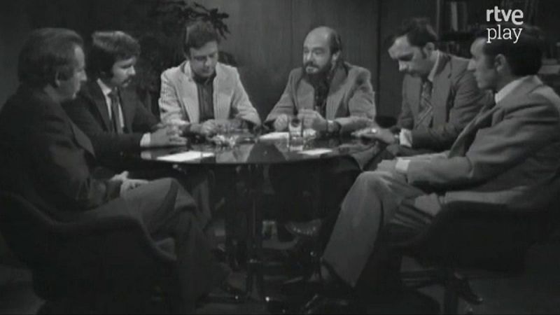 Seis hombres en un estudio de TV, alrededor de una mesa redonda, debatiendo. Presenta a Fernando Jiménez del Oso, conductor de "Más allá". Logo "rtve play" visible. Fotografía en blanco y negro, 1976-1981.