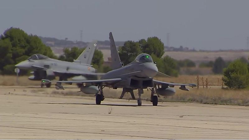 Dos Eurofighter Typhoon de la Fuerza Aérea Española en pista. El primero con luces verdes, el segundo le sigue. Entorno seco, cielo claro.