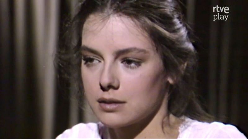 Lola Forner en su juventud, primer plano con expresi�n serena. Cabello casta�o oscuro, vestimenta clara con encaje. Logo "rtve play" visible.