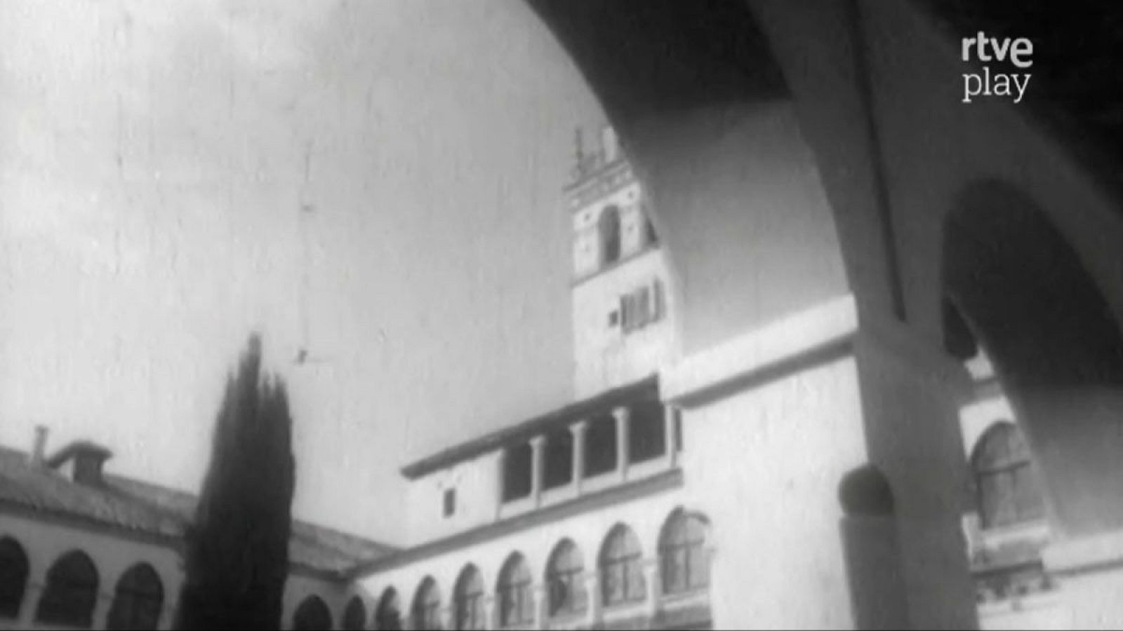 Interior de monasterio en blanco y negro, con arcos, edificio de tonos claros, torre cuadrada, árbol esbelto y logo "rtve play".
