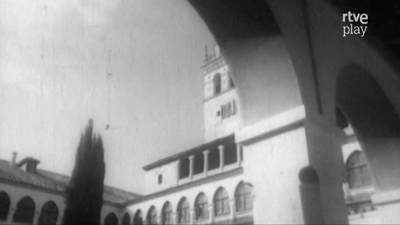 Interior de monasterio en blanco y negro, con arcos, edificio de tonos claros, torre cuadrada, árbol esbelto y logo "rtve play".