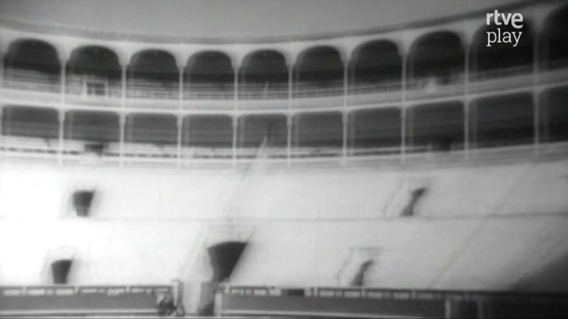 Plaza de toros vacía en blanco y negro, con gradas claras, galerías con arcos oscuros y el logo "rtve play" en la esquina superior derecha.