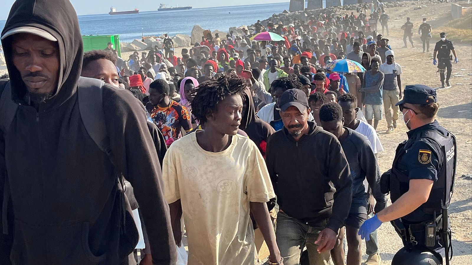 La Policía desaloja a los migrantes de la playa del Trampolín y los traslada a dos espacios habilitados por el Gobierno Cientos de migrantes son desalojados de la playa del Trampolín en Ceuta tras habilitarse un espacio para su acogida este jueves