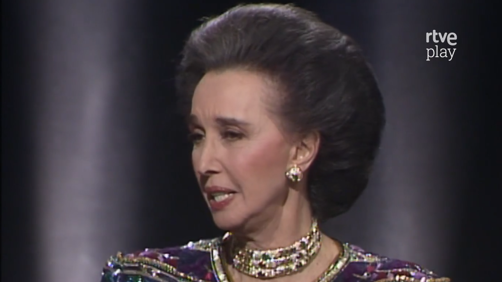 Retrato de la Condesa de Romanones, Aline Griffith, de perfil, con atuendo brillante y collar llamativo. Logo de "rtve play" en la imagen.