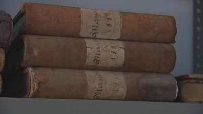 Tres vol�menes antiguos apilados, con etiquetas que muestran "1881" y "Manuscrito" escrito a mano. El estado de los libros indica su antig�edad.