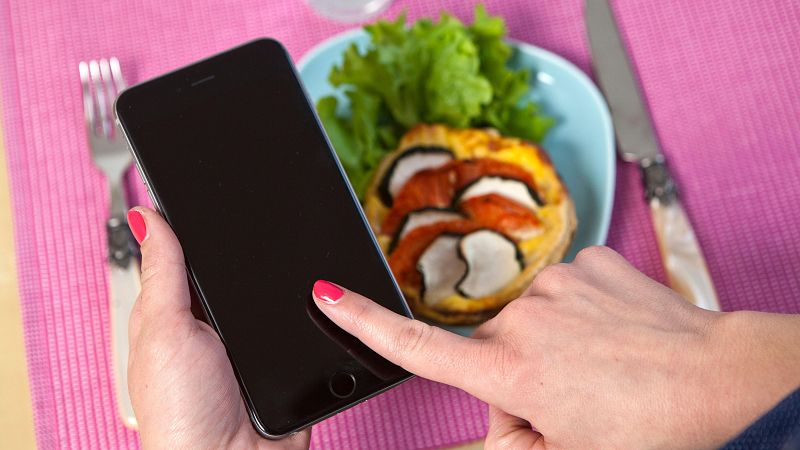 Una persona hace uso del movil durante la comida