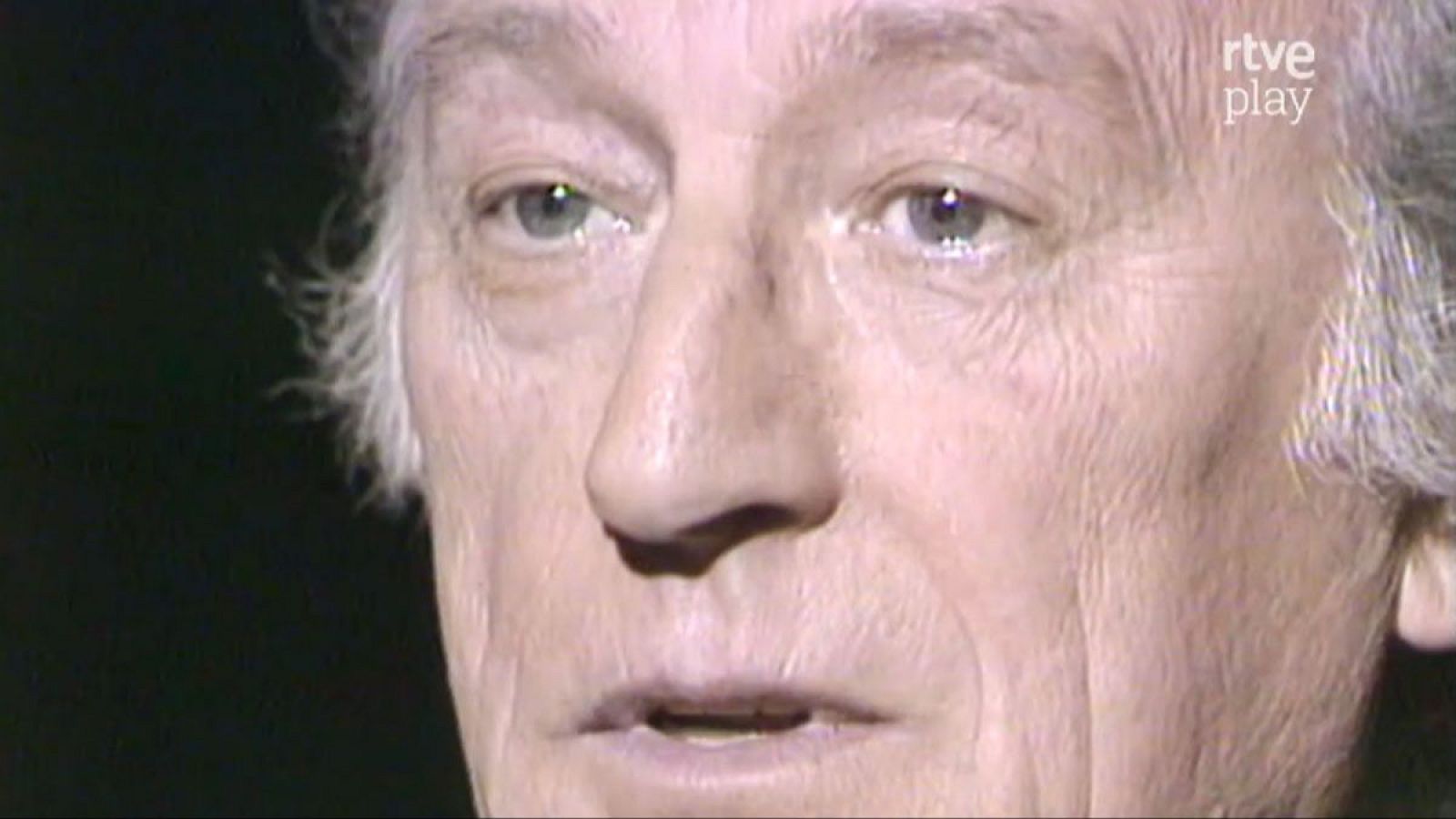 Primer plano frontal del rostro de Antonio Mingote, de edad avanzada, con cabello canoso y mirada clara. Fondo oscuro con logo de "rtve play".