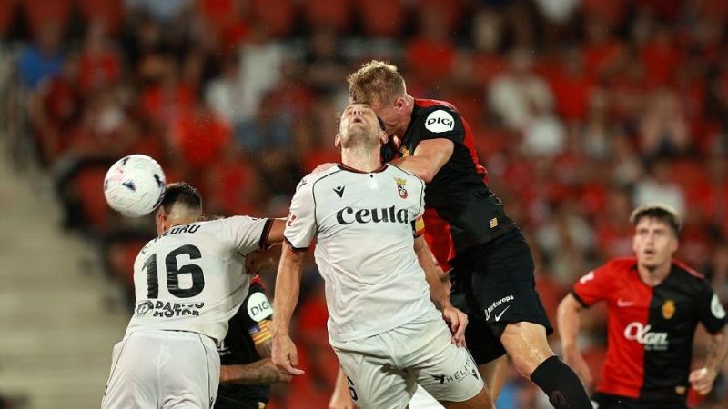 Jugadores de AD Ceuta FC y RCD Mallorca compiten por el bal�n en un partido de f�tbol. Pedro L�pez (16) de Ceuta disputa el esf�rico con un rival mallorqu�n. Gradas llenas al fondo.
