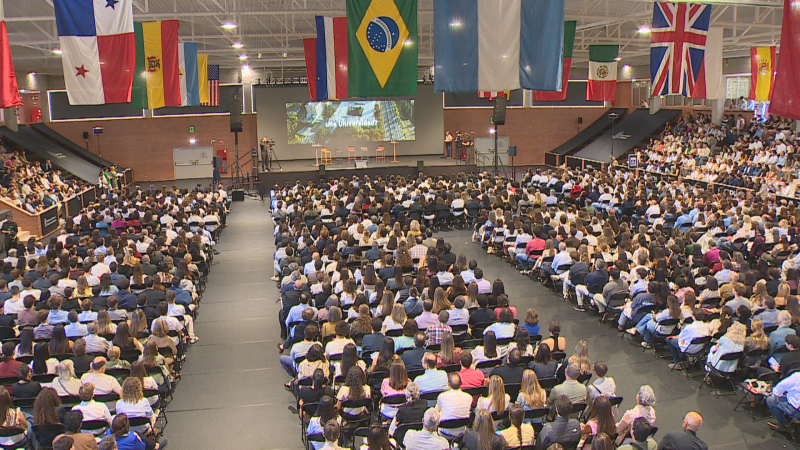 Evento en auditorio con audiencia y escenario. Pantalla muestra "UNAV Universidad". Banderas de Panamá, Colombia, Brasil, Francia, México, Reino Unido y España.