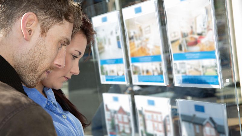 Una pareja delante de una inmobiliaria