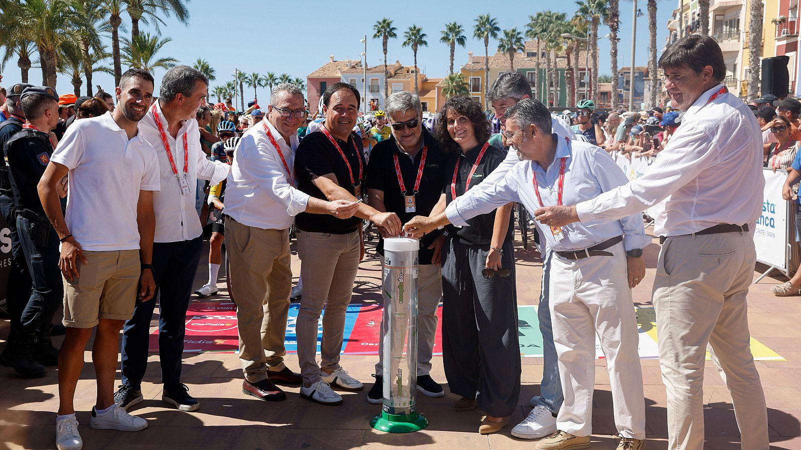 Alejandro Valverde participa en un sorteo o acto ceremonial en la Costa Blanca, introduciendo objetos en una urna junto a otras personas.