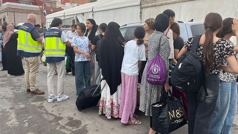 Agentes de Policía Nacional supervisan a un grupo de mujeres y niñas con equipaje en una explanada. Se observan maletas y bolsas de marcas como Polo Ralph Lauren y M&S FOOD.