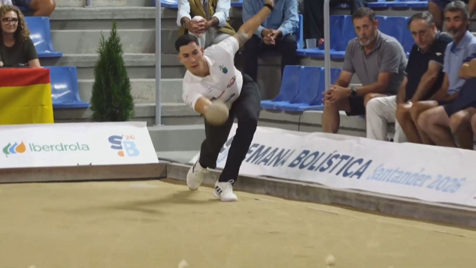 Victor González lanza una bola de bolos en un partido, con concentración. Viste polo blanco y pantalón negro. Al fondo, gradas y banners publicitarios con "SEMANA BOLÍSTICA Santander 2026".