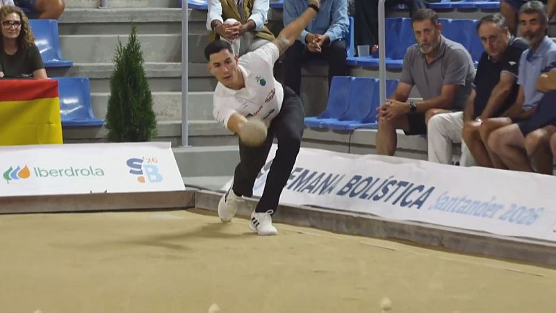 Victor González lanza una bola de bolos en un partido, con concentración. Viste polo blanco y pantalón negro. Al fondo, gradas y banners publicitarios con "SEMANA BOLÍSTICA Santander 2026".