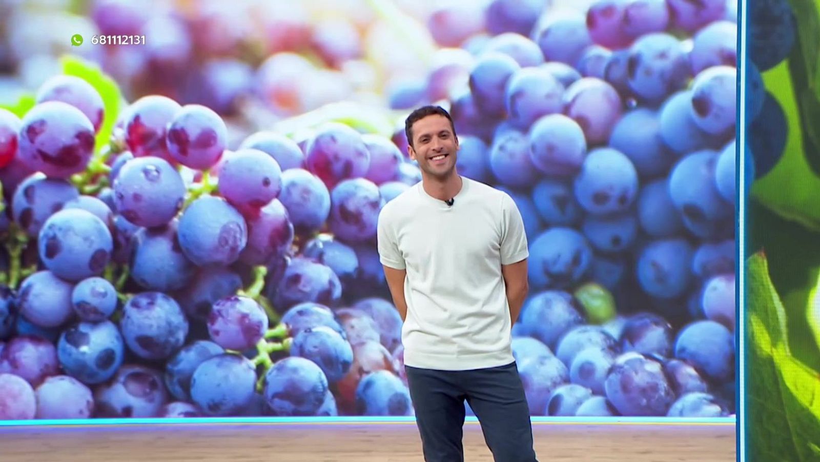 Juanma López Iturriaga, presentador, en un plató con pantalla de uvas moradas y logo de WhatsApp con número 681112131.